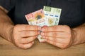 Mexico money, a man in a shirt behind a desk holds 100 and 200 pesos banknotes in his hand, Business investments, Creative