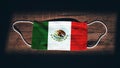 Mexico National Flag at medical, surgical, protection mask on black wooden background. Coronavirus CovidÃ¢â¬â19, Prevent infection,