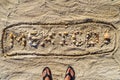 Mexico spelled out in seashells in the sand, above feet in sandals Royalty Free Stock Photo