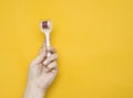 Mezoroller, dermaroller, mesotherapy skin tool in a woman`s hand on a yellow background. Copy space