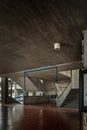 mezzanine, large empty room, brutalist architecture, with ceiling lamps, stairs and a red tile floor.