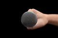 Mic - Close-up of the dynamic microphone held with one hand on an isolated black background Royalty Free Stock Photo