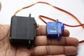 Micro servo and metal geared servo held in hand. Servo which has high torque and slow rpm controlled digitally with micro