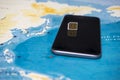 Micro SIM card and smartphone on the world map Royalty Free Stock Photo