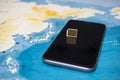 Micro SIM card and smartphone on the world map Royalty Free Stock Photo