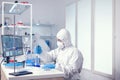 Microbiologist dressed in coverall using automatic pipette