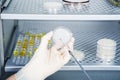 Microbiologist hand cultivating a petri dish whit inoculation loops, beside autoclave.