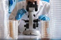 Microbiologist with microscope working with petri dish in the la