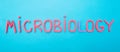 Microbiology word laid out on a blue background from red plasticine, science concept bacteriology, mycology, virology,