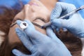 Microblading close-up, hands adding pigment to eyebrows, woman head face Royalty Free Stock Photo