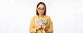 Microcredit and money concept. Stylish asian young woman in sunglasses, laughing happy, holding dollars cash, standing Royalty Free Stock Photo