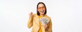 Microcredit and money concept. Stylish asian young woman in sunglasses, laughing happy, holding dollars cash, standing Royalty Free Stock Photo