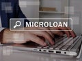 MICROLOAN text in search bar. Loan officer looking for something at laptop. MICROLOAN concept Royalty Free Stock Photo