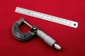 Engineering Micrometer and Steel Ruler on a Red Table Surface Royalty Free Stock Photo