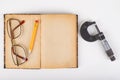Micrometer and old book with glasses on a white table. Workshop accessories Royalty Free Stock Photo