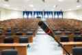 Microphone with blurred photo of empty conference hall or seminar room in background. Business meeting concept Royalty Free Stock Photo