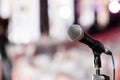 Microphone close-up. Focus on mic. Abstract blurred conference hall or wedding banquet on background. Event concept