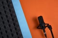 Microphone on double color blue and orange background and acoustic foam panel Royalty Free Stock Photo