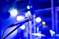 Microphone on empty stage with multi colored blurred background lights