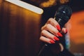 Microphone and female singer close up. Woman singing into a microphone, holding mic with hands. Royalty Free Stock Photo