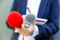 Microphone in focus, female reporter at news conference writing notes. Public relations PR concept. Royalty Free Stock Photo