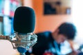 Microphone on focus, playing young guitarist on background in a small music studio Royalty Free Stock Photo