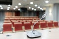 Microphone in the foreground. Seminar presentation. Conference room full of empty seats. Red color. Hall for workshops Royalty Free Stock Photo