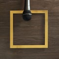 Microphone on a gold frame on a wooden background. Text space. Top view. Minimal style Royalty Free Stock Photo