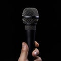 Microphone in hand on a black background, close-up. Royalty Free Stock Photo