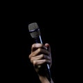 Microphone in hand on a black background, close-up. Royalty Free Stock Photo