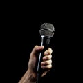 Microphone in hand on a black background, close-up. Royalty Free Stock Photo
