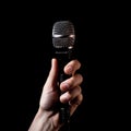 Microphone in hand on a black background, close-up. Royalty Free Stock Photo