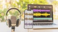 Microphone, headphones, and smartphone displaying audio waveforms with laptop editor. Concept of artificial intelligence voice Royalty Free Stock Photo