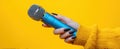 The microphone held by a stylish hand against a vibrant yellow background..AI generated image Royalty Free Stock Photo