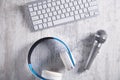 Microphone, keyboard and headphones on a white desk. Top View