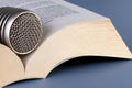 Microphone lying on open book on a dark gray background.Close up.Soft focus.Concept of audio recording of print media, dubbing,