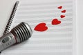 Microphone and paper red hearts are located on a clean music notebook. The concept of music and love. Valentine`s day Royalty Free Stock Photo