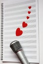 Microphone and paper red hearts are located on a clean music notebook. The concept of music and love. Valentine`s day Royalty Free Stock Photo