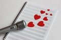 Microphone and paper red hearts are located on a clean music notebook. The concept of music and love. Valentine`s day Royalty Free Stock Photo