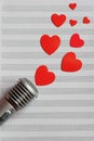 Microphone and paper red hearts are located on a clean music notebook. The concept of music and love. Valentine`s day Royalty Free Stock Photo