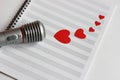 Microphone and paper red hearts are located on a clean music notebook. The concept of music and love. Valentine`s day Royalty Free Stock Photo