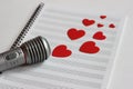 Microphone and paper red hearts are located on a clean music notebook. The concept of music and love. Valentine`s day Royalty Free Stock Photo