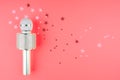 Microphone on a pink background with confetti. Living Coral Color of the year 2019. Royalty Free Stock Photo