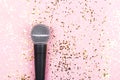 A microphone on pink background decorated with confetti. Minimal compostion. Royalty Free Stock Photo