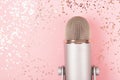 A microphone on pink background decorated with confetti. Minimal compostion. Royalty Free Stock Photo