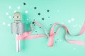 Microphone with a pink ribbon on a green background with confetti. Royalty Free Stock Photo