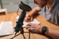 Microphone with pop filter closeup photo with a man reading the text and recording voice using a desktop computer. Modern home Royalty Free Stock Photo