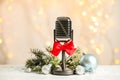 Microphone with red bow and decorations on  table against blurred lights. Christmas music Royalty Free Stock Photo