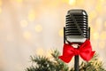 Microphone with red bow and fir branches against blurred lightst. Christmas music