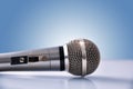 Microphone with reflections on white glass table and blue background Royalty Free Stock Photo